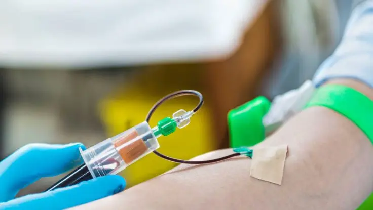 A person wearing white gloves is carrying a tube filled with liquid, like medicine or chemicals.